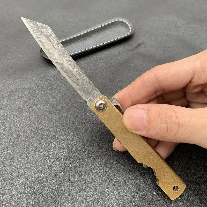 Couteau pliant Higonokami avec une lame en damas et un manche doré, idéal pour les amateurs de coutellerie.