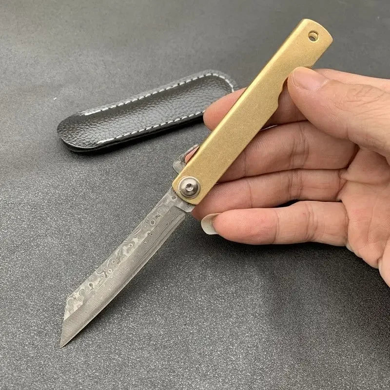 Couteau pliant Higonokami avec manche doré et lame en acier damassé, idéal pour les amateurs d'outils élégants.